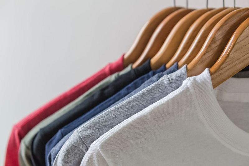 Camisetas de colores en perchas de madera, símbolos de lavado por revisar