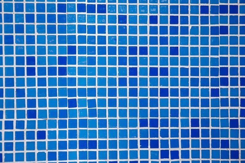 Mosaico de vidrio azul en el baño con juntas claras entre las teselas