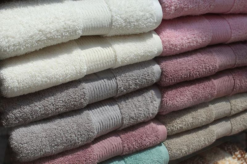 Toallas de rizo suaves apiladas en blanco, gris y rosa tras el lavado