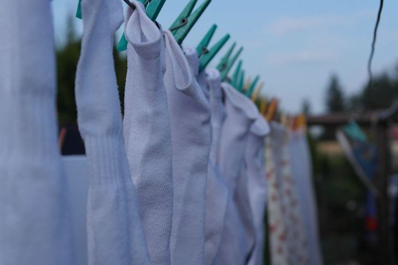Calcetines blancos recién lavados colgados con pinzas en el tendedero