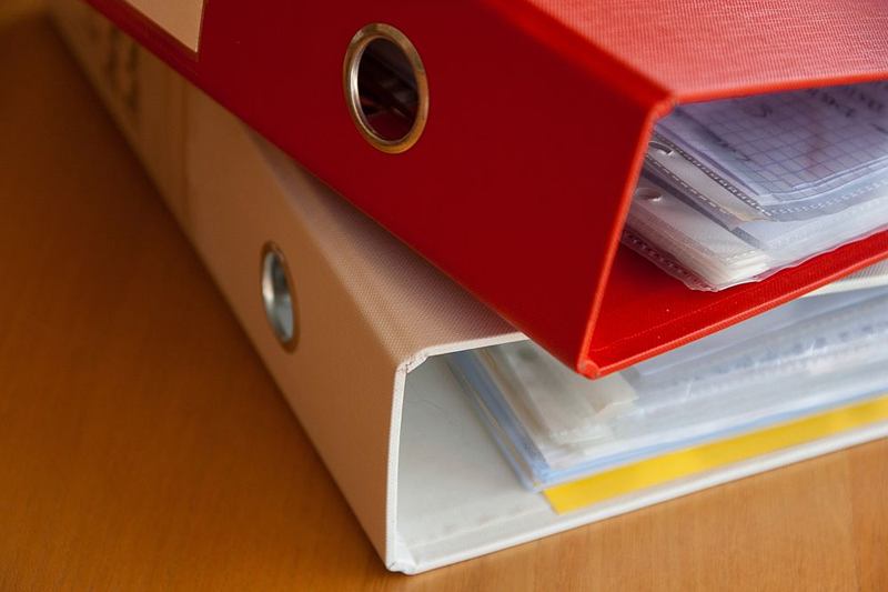 Archivadores rojo y blanco llenos de documentos, listos para la solicitud de alquiler