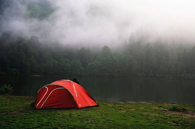 Tienda roja junto a un lago con niebla, que debe secarse antes de guardarla